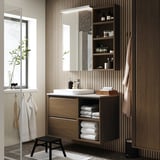 Moderne badkamer met houten kast en marmeren wastafel, met open en gesloten opslag, handdoeken en planten.
