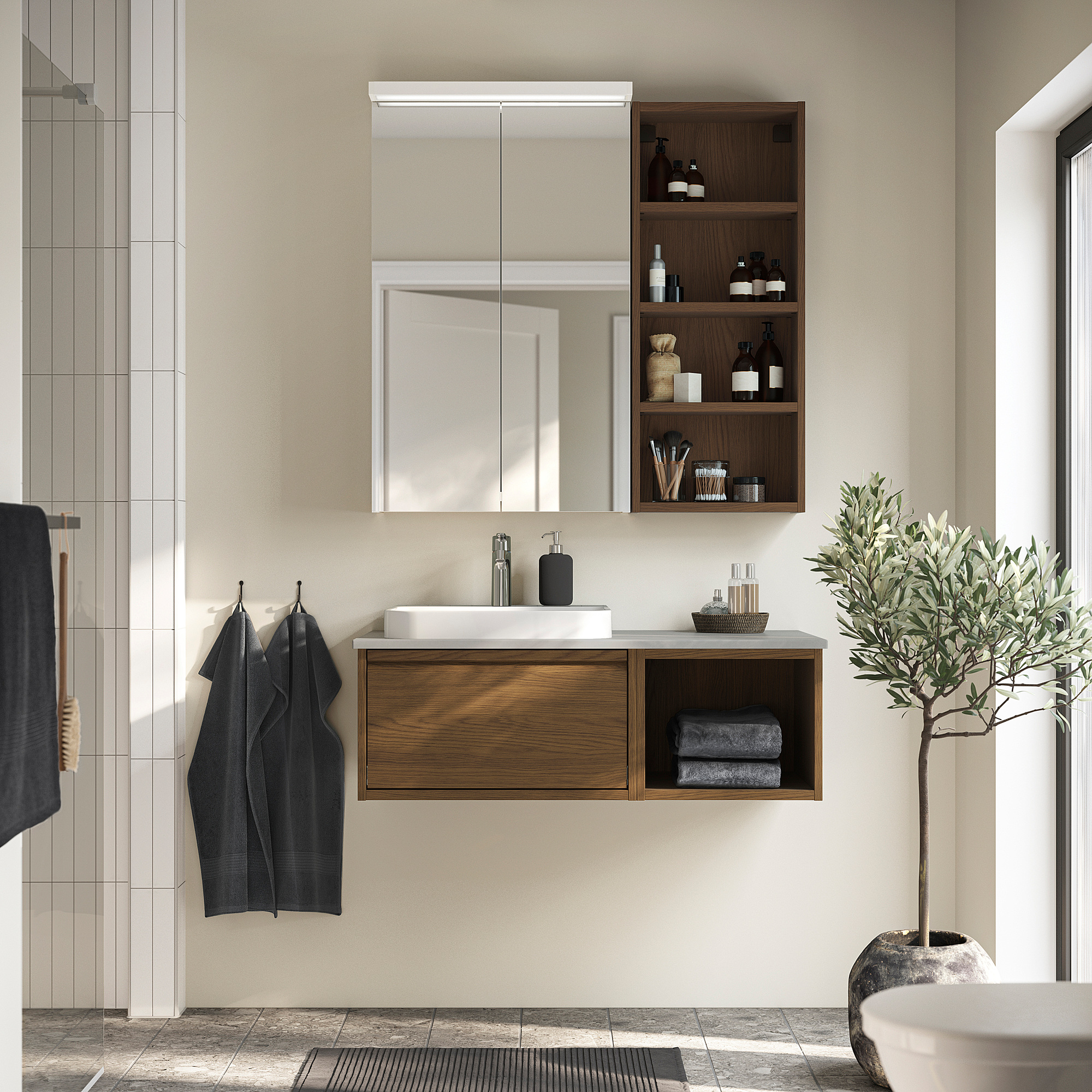 Moderne badkamer met ÄNGSJÖN houten wastafel, spiegel, wastafel, handdoeken en plant.