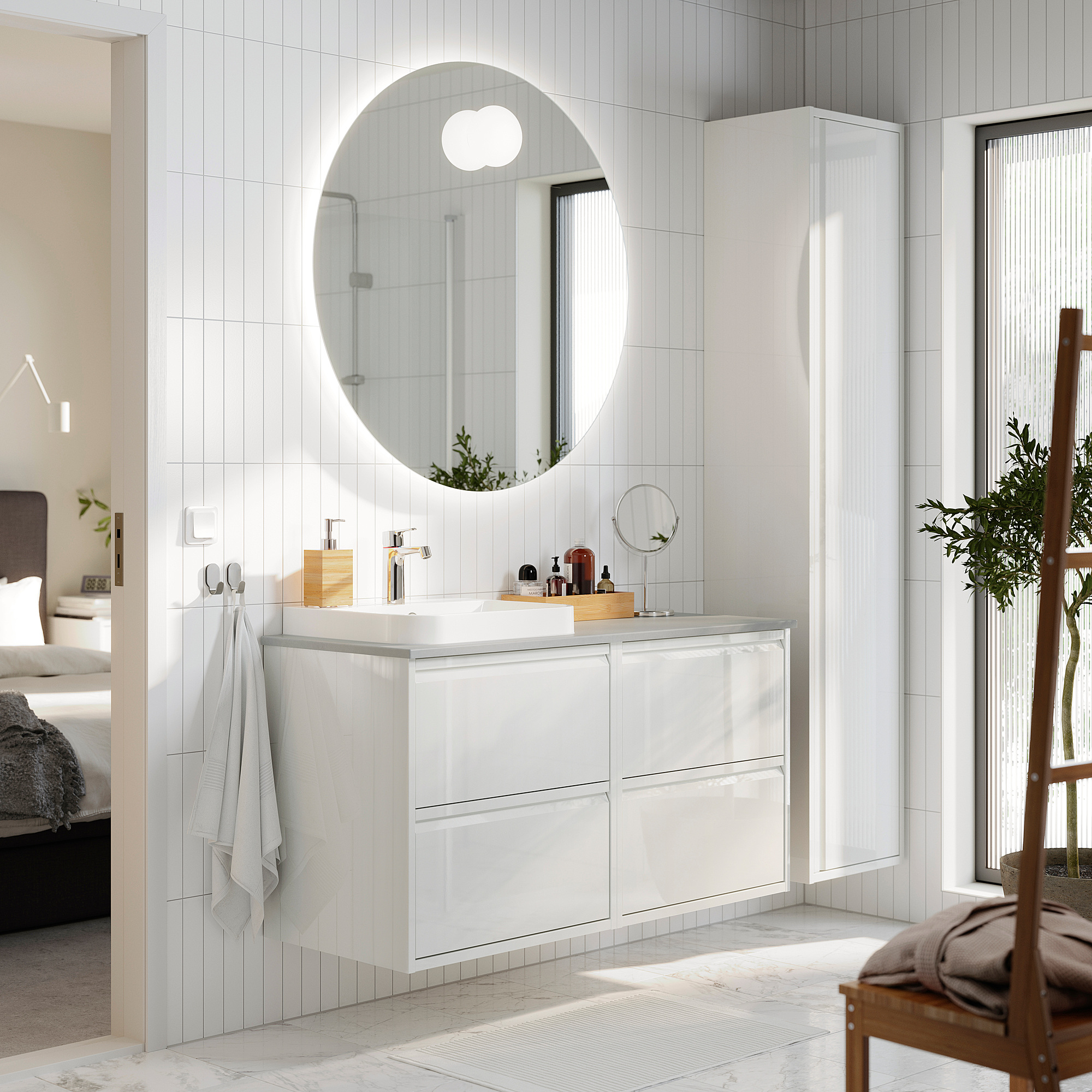 Moderne witte badkamer met glanzende ÄNGSJÖN ijdelheid, ronde spiegel en potplant.