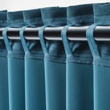 Teal kamerverduisterende gordijnen hangen met haken, blokkeren het licht en zorgen voor privacy.