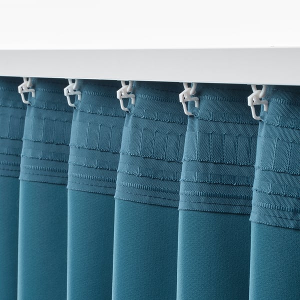 Teal kamerverduisterende gordijnen hangen aan een witte roede met haken, die het licht blokkeren en privacy bieden.