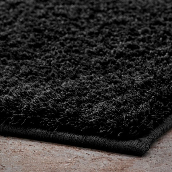 Zachte, pluche zwarte badmat gemaakt van gerecycled polyester met latex achterkant voor stabiliteit.