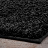 Zachte, pluche zwarte badmat gemaakt van gerecycled polyester met latex achterkant voor stabiliteit.