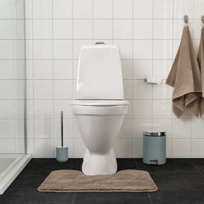 Beige BACKMÅRA badmat in schone badkamer, ligt voor het toilet, vormt een aanvulling op handdoeken.