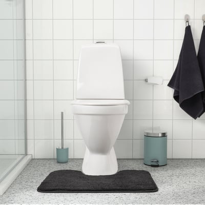 Wit toilet op zwarte mat, aquabrush en prullenbak. Mat: BACKMÅRA, donkergrijs, 100% polyester, dik, zacht.