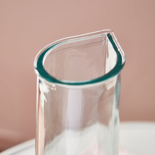 Cilindrische glazen karaf met groene tint, glad oppervlak en smalle tuit.