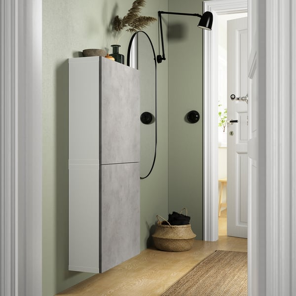 Smalle BESTÅ unit met 2 deuren op groene muur, witte deuren, zwarte lamp, mand met handdoeken.