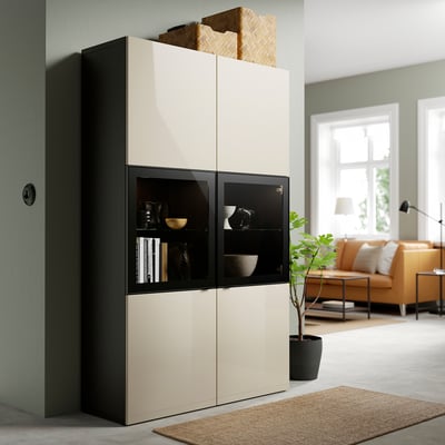 Moderne woonkamer met BESTÅ kast, decor, glazen deuren, planken, rieten mand, oranje bank en plant.