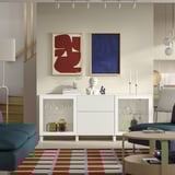 Moderne woonkamer met BESTÅ-wit dressoir, kunst, blauwe bank, trap, tapijt, railverlichting.