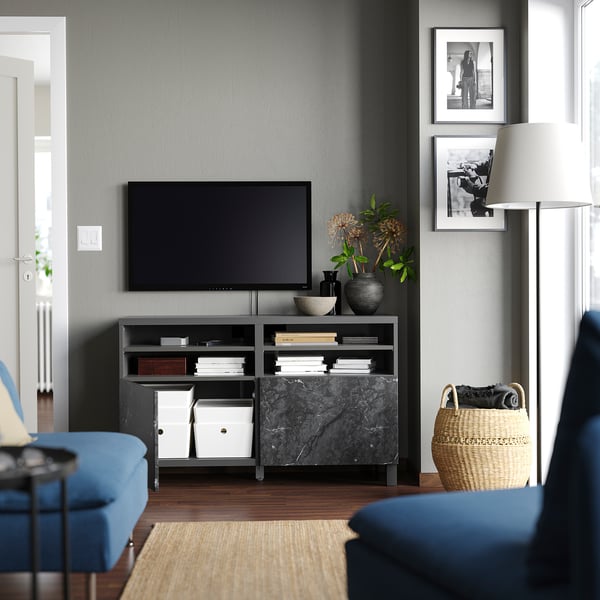 Moderne woonkamer met zwart BESTÅ tv-meubel, marmeren blad, bloemen, boeken, foto's, blauwe bank en mand.