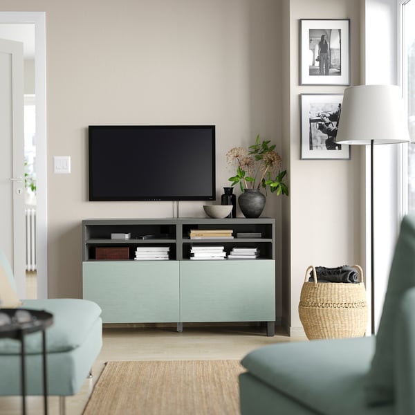 Moderne woonkamer met mintgroene BESTÅ tv-meubel, flatscreen-tv, decoratieve vazen, fotolijsten, rieten mand en groenblauwe meubels.