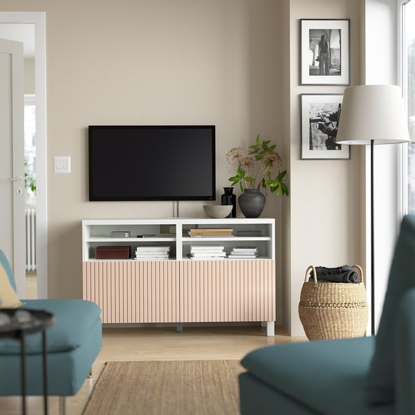 Moderne woonkamer met BESTÅ tv-meubel, groenblauwe fauteuils, flatscreen-tv, boeken, opbergruimte, mand, lamp, vazen, foto's.