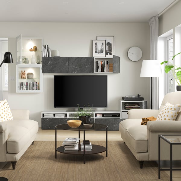 Moderne woonkamer met witte banken, salontafel en tv-meubel. Het tv-meubel heeft verstelbare planken, kabelbeheer en wandkasten voor opslag.