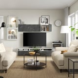 Moderne woonkamer met witte banken, salontafel en tv-meubel. Het tv-meubel heeft verstelbare planken, kabelbeheer en wandkasten voor opslag.