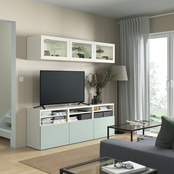 Moderne woonkamer met BESTÅ wit tv-meubel, grijze bank, glazen salontafel en vloerlamp.