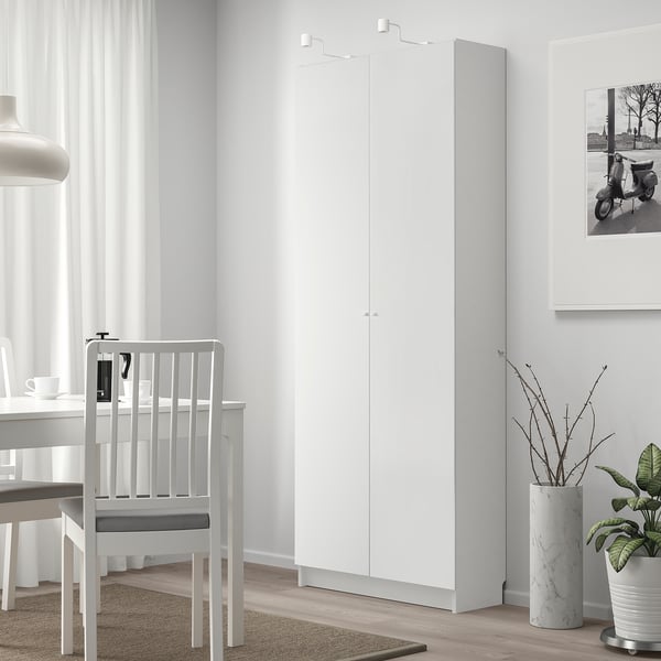 Witte BILLY boekenkast naast tafel en stoel, hoger met verstelbare planken.