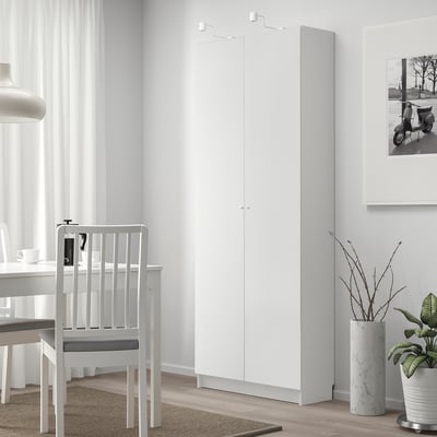 Witte BILLY boekenkast naast tafel en stoel, hoger met verstelbare planken.