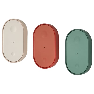 Drie ovaalvormige afstandsbedieningen in beige, roestrood en groenblauw, gemaakt van kunststof, horizontaal geplaatst.