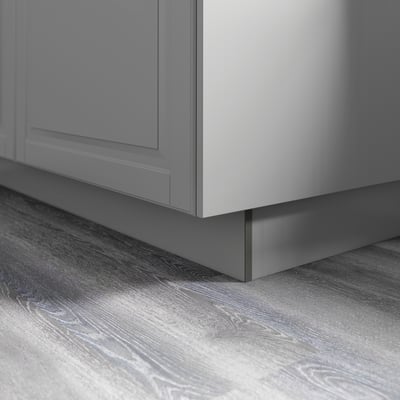 Grijze keukenkast met gladde gelakte afwerking, bevestigd aan een houten vloer met zichtbare nerf, die een minimalistische stijl en een gemakkelijk schoon te maken oppervlak demonstreert.