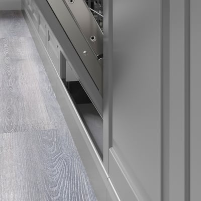 Detail van de keukenkast met strakke, grijze BODBYN-panelen met afgeschuinde randen en een plint onder de kast.