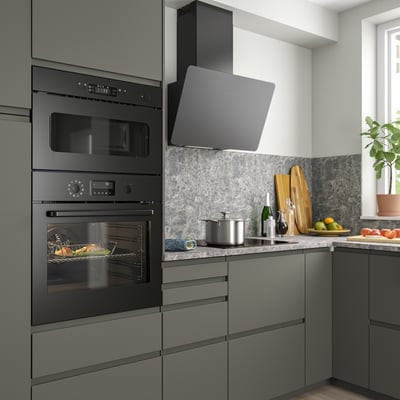 Moderne keuken met zwarte BRÄNDBO oven, magnetron en grijze kasten; Strakke apparaten domineren de aanrechtruimte.