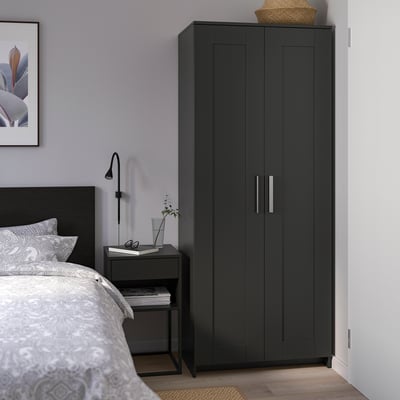 Moderne zwarte BRIMNES kledingkast tussen ikea bed en bijzettafel, stijlvol en praktisch opbergen.