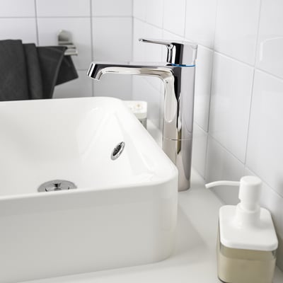 BROGRUND chromen kraan staat hoog naast een witte gootsteen met zeepdispenser.