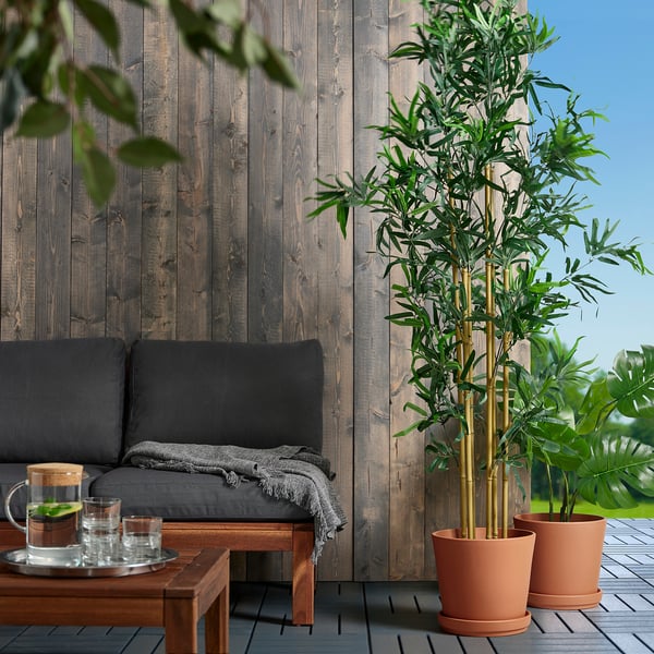 Gezellige patio met grote zwarte bank, BRUNBÄR terracotta potten met hoge planten, houten wand. Potten zijn groot en zeer geschikt voor buitengroen.