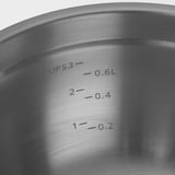Close-up van een roestvrijstalen kom met gegraveerde afmetingen voor kopjes en liters, wat wijst op hoogwaardig en nauwkeurig ontwerp.