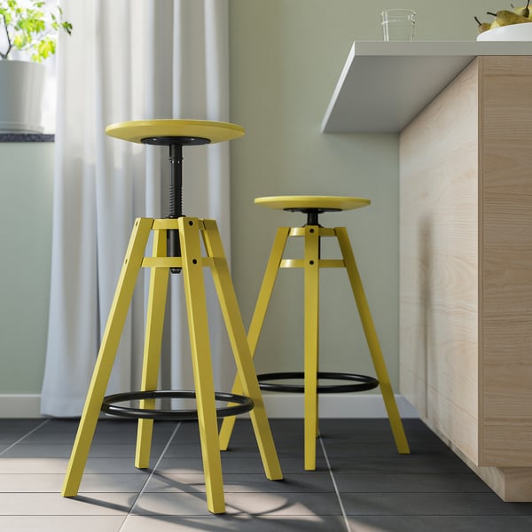 Twee felgele DALFRED krukken in moderne keuken, in hoogte verstelbaar, driepoot design.