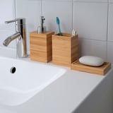 Moderne wastafel in de badkamer met chromen kraan, houten zeepdispenser, tandenborstelhouder en zeepbakje. Bamboe houten accessoires zorgen voor een warme, natuurlijke uitstraling.
