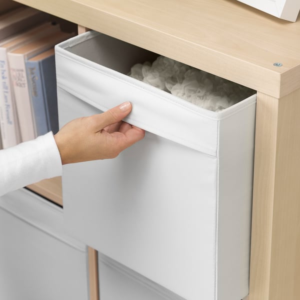 Hand trekt witte DRÖNA opbergdoos uit de plank en onthult de inhoud.