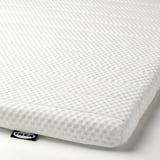 Close-up van een witte, getextureerde matrashoes met duidelijke tags die merk en kwaliteit aangeven.