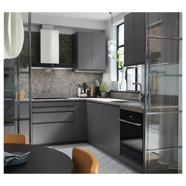 Moderne keuken met donkergrijs EKBACKEN aanrechtblad, strakke kasten, RVS apparatuur en hanglamp. Oranje stoelen voegt kleurcontrast toe.