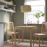 Gezellige eetopstelling met een houten tafel, stoelen, planken en een unieke lamp.