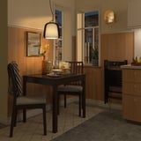 Gezellige eetkamer met zwarte EKEDALEN tafel, twee stoelen en hanglamp. Houten vloeren en warme verlichting.