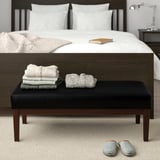 EKENÄSET zwarte retro bank met handdoeken, slippers, onder groot bed.