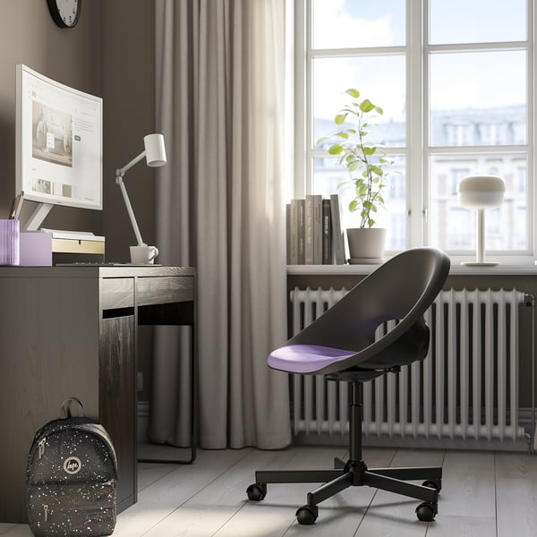 Thuiskantoor met ELDBERGET zwarte bureaustoel, modern & comfortabel, past onder bureau, bij raam met plant, computeropstelling.