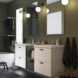 Elegante badkamer met een dubbele gebroken witte ENHET wastafel, ruime en moderne, contrasterende groene wanden.