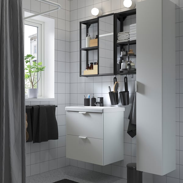 Moderne badkamer met ENHET witte kast, strakke wastafel en spiegel. Zwarte accenten zijn onder andere handdoeken en accessoires. Kleine maar georganiseerde ruimte.