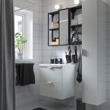 Moderne badkamer met ENHET witte kast, strakke wastafel en spiegel. Zwarte accenten zijn onder andere handdoeken en accessoires. Kleine maar georganiseerde ruimte.