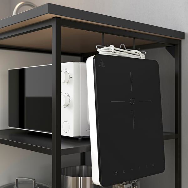 Zwarte keukenplank met magnetron, tabletstandaard en ophangsnoeren.