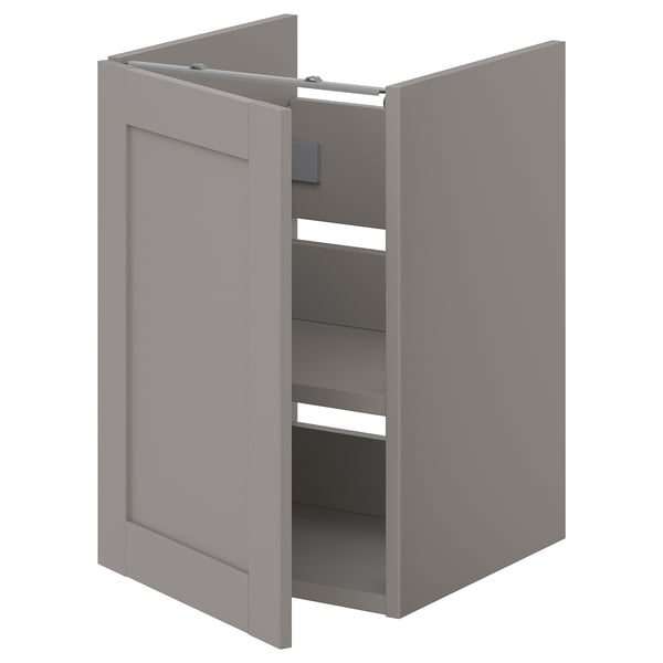Deze afbeelding toont een grijze ENHET badkamerkast met één deur open, waardoor planken binnenin zichtbaar worden. De kast is rechthoekig met gladde oppervlakken.
