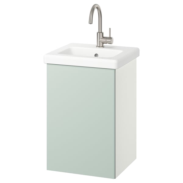 Een lichtgroen badkamermeubel aan de muur met een witte wastafel en zilveren kraan.