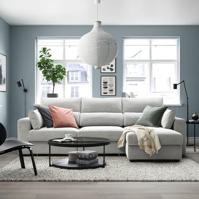 Grijze ESKILSTUNA sectionele bank, pluche kussens, hoge rugleuningen, met salontafel en vloerkleed in moderne woonkamer.