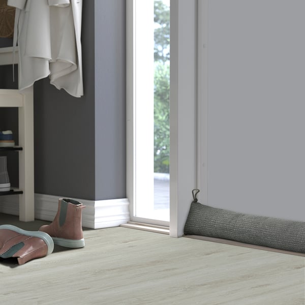 Kleine sneakers door deur met tochtstopper, kleding, mand.