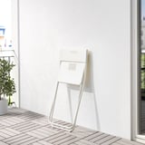Opvouwbare witte stoel op betegeld balkon, perfect voor kleine ruimtes.