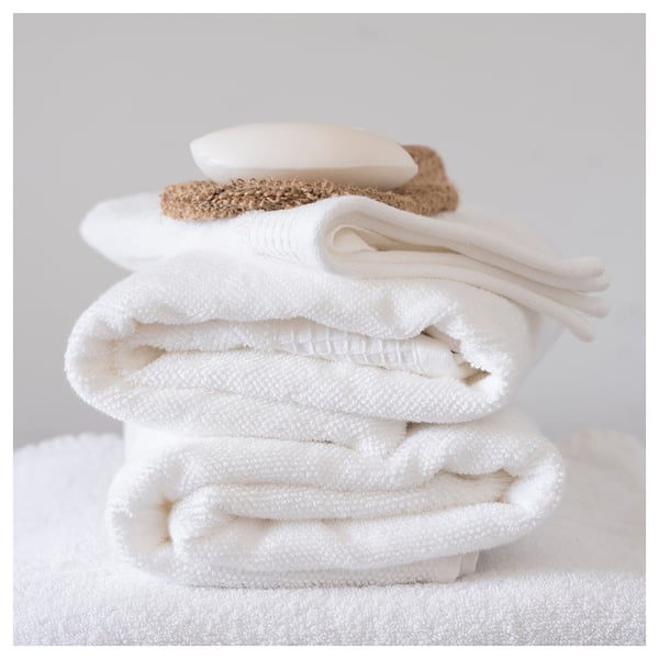 Stapel gevouwen witte handdoeken met badaccessoires. Schone, frisse uitstraling.