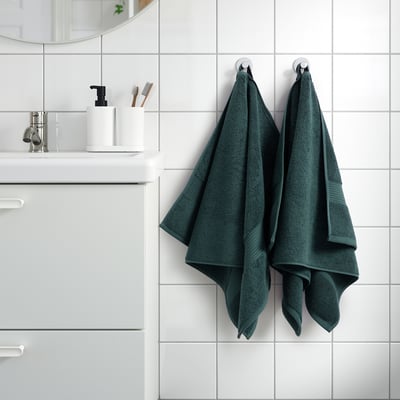 De donkergroene handdoeken van FREDRIKSJÖN hangen netjes in de buurt van de gootsteen en hebben hun dikke, 100% katoenen textuur en elegante geweven rand, groter dan items in de buurt.