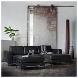 Moderne woonkamer met zwarte lederen bank, schuifdeur, plant, laptop.